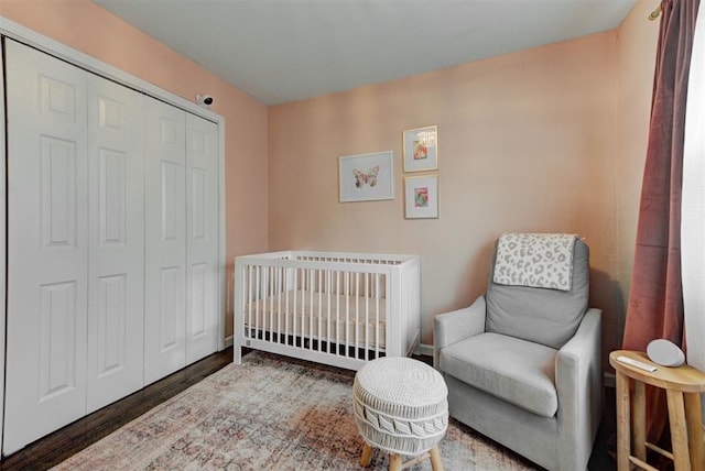 bedroom featuring a crib, a closet, and wood finished floors