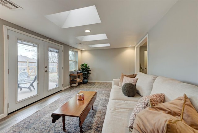 living area featuring a skylight, visible vents, french doors, light wood-type flooring, and recessed lighting