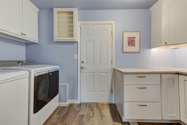 laundry room featuring cabinet space, washer and clothes dryer, baseboards, and wood finished floors