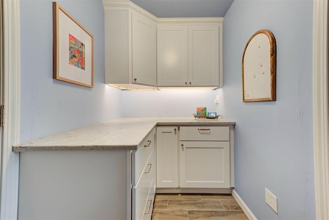 kitchen with baseboards, white cabinets, and wood finish floors