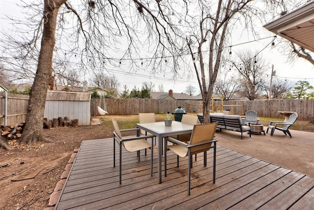 deck featuring an outbuilding, outdoor dining area, a fenced backyard, and a storage unit