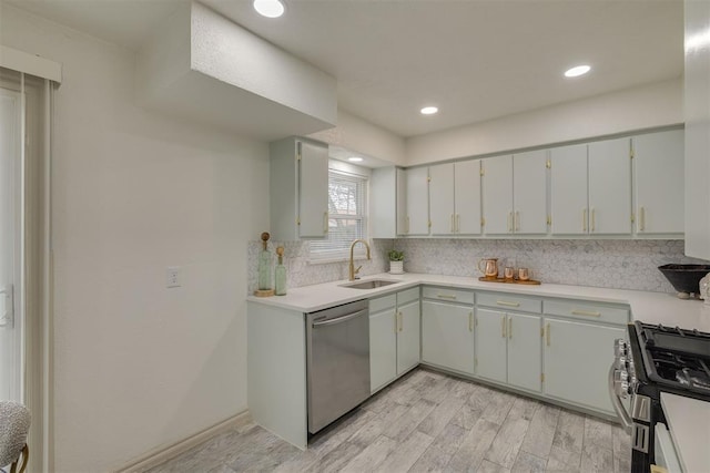 kitchen with tasteful backsplash, appliances with stainless steel finishes, light countertops, light wood-style floors, and a sink