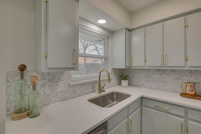 kitchen featuring tasteful backsplash, light countertops, and a sink