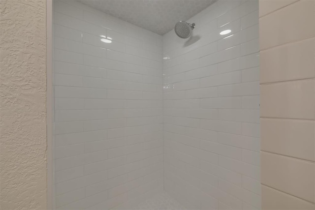 interior details with tiled shower and a textured wall