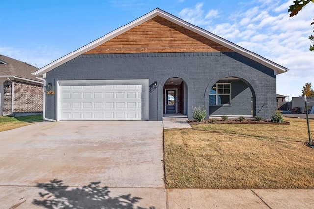 view of front of house with a garage, a front yard, concrete driveway, and brick siding