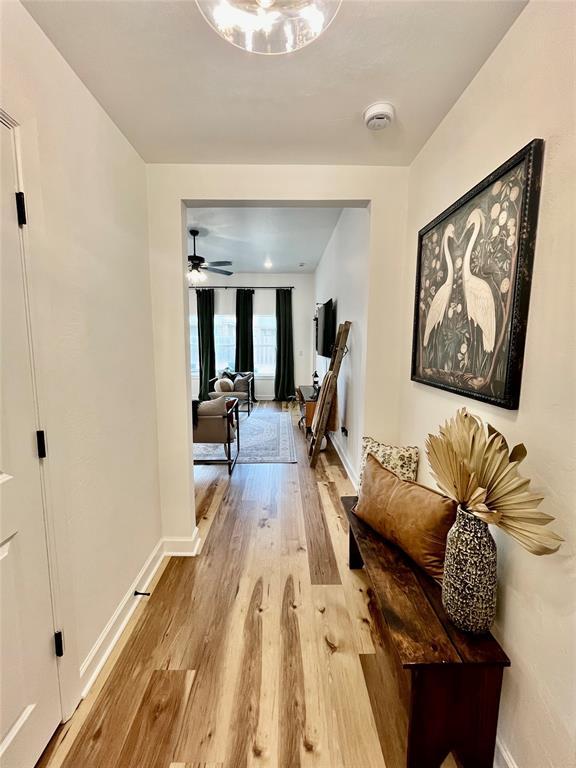 hallway with light wood-type flooring and baseboards