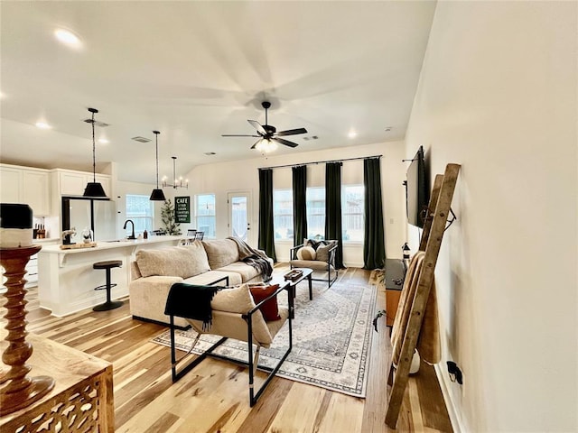 living room with ceiling fan, light wood finished floors, and visible vents