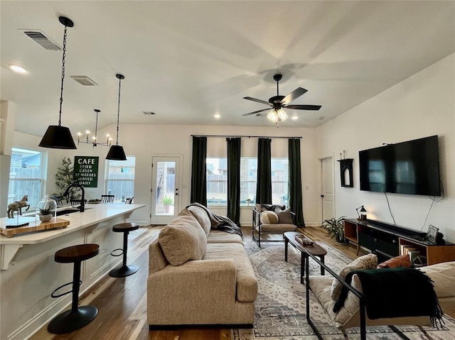 living area with baseboards, wood finished floors, visible vents, and a ceiling fan