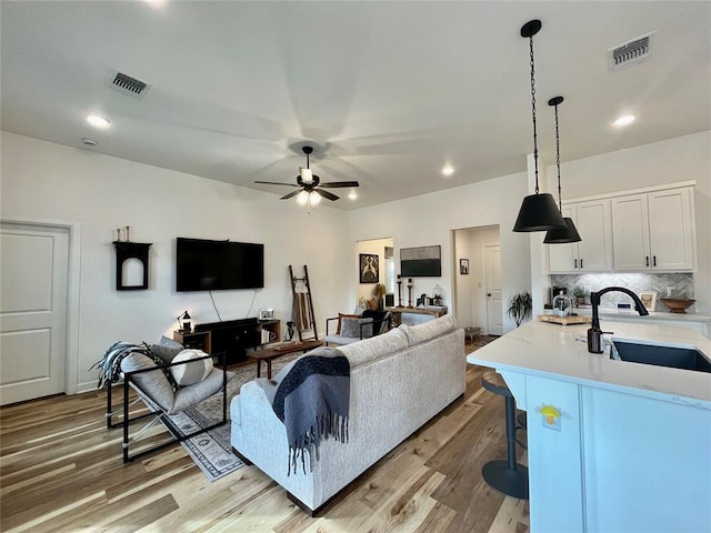 living area with light wood-style flooring, visible vents, ceiling fan, and recessed lighting