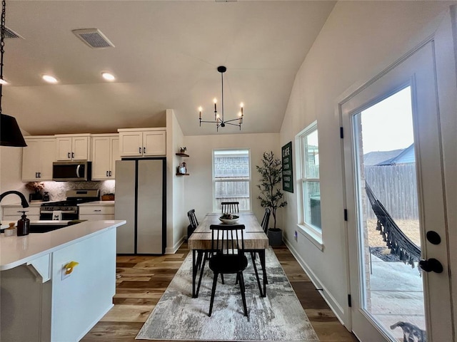 interior space featuring lofted ceiling, dark wood-style flooring, visible vents, and a notable chandelier