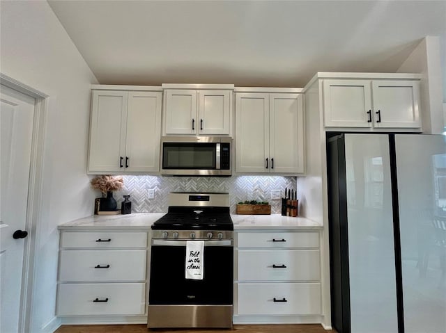 kitchen featuring stainless steel appliances, light countertops, white cabinetry, and decorative backsplash