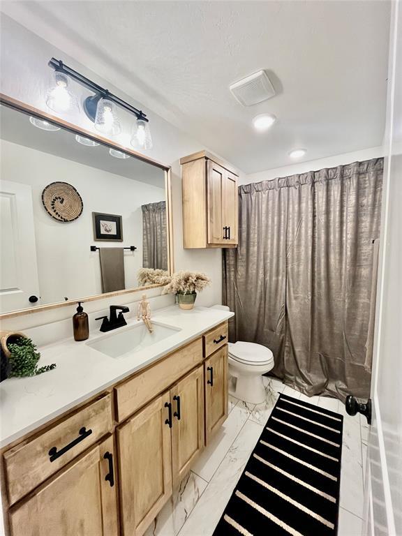 full bathroom featuring marble finish floor, vanity, and toilet