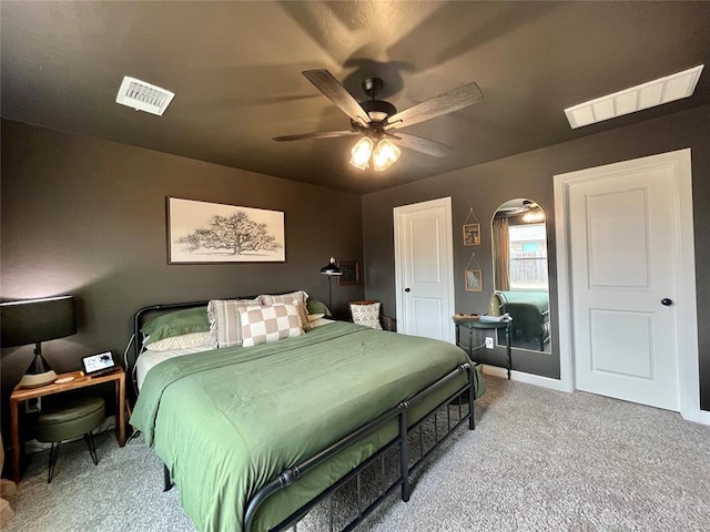 bedroom featuring a ceiling fan, visible vents, and light colored carpet