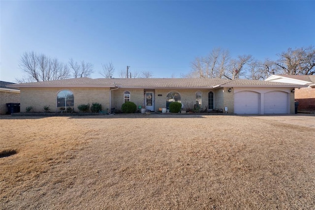 ranch-style home with an attached garage, brick siding, and driveway