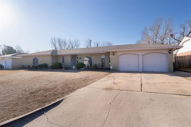 single story home with concrete driveway, fence, brick siding, and a garage