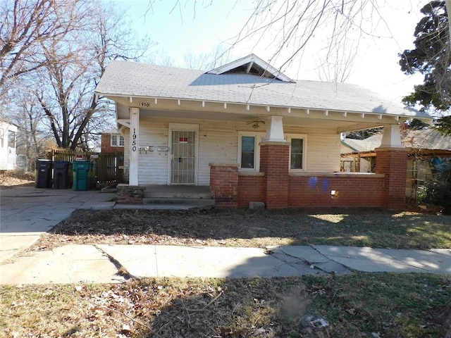 bungalow-style house featuring covered porch, fence, and brick siding