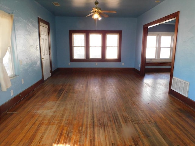 empty room with a ceiling fan, wood-type flooring, visible vents, and baseboards