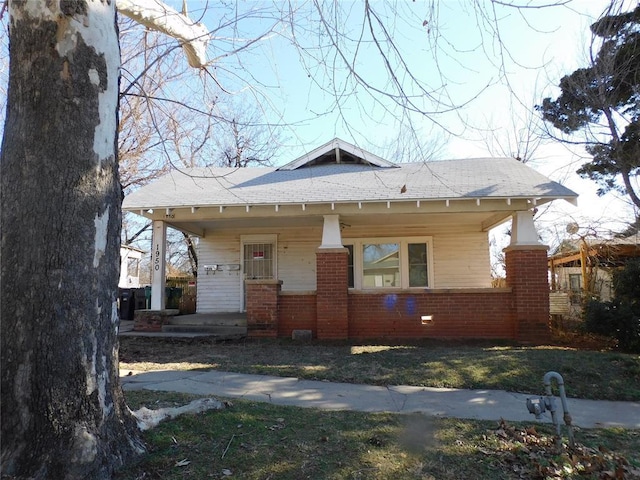 bungalow featuring a porch and brick siding