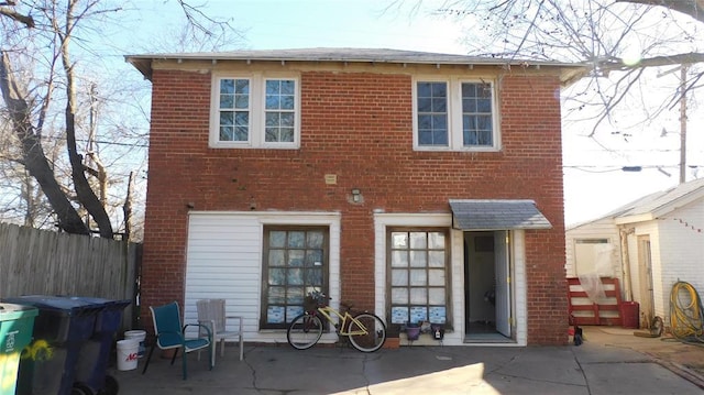 back of property featuring fence, a patio, and brick siding