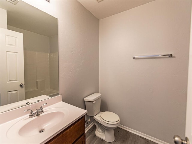 full bathroom with toilet, wood finished floors, vanity, baseboards, and a shower