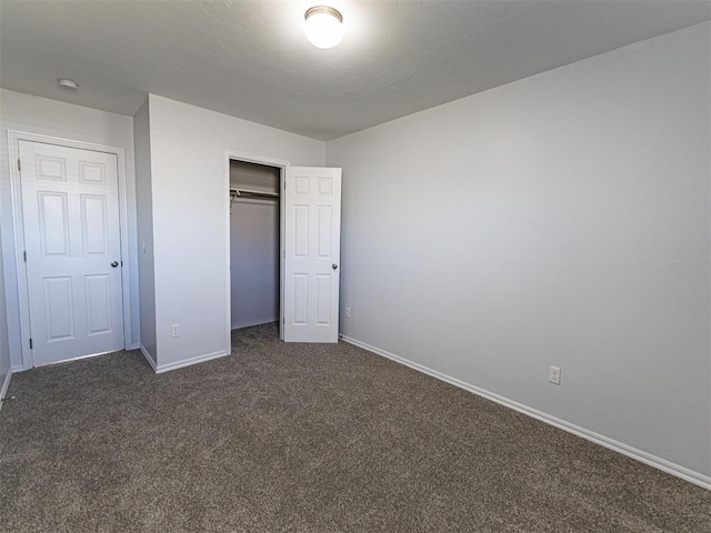 unfurnished bedroom featuring dark colored carpet, a closet, and baseboards