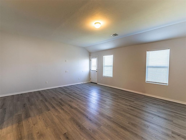 spare room featuring baseboards, vaulted ceiling, visible vents, and dark wood finished floors