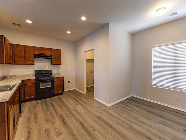 kitchen featuring black appliances, range hood, visible vents, and wood finished floors