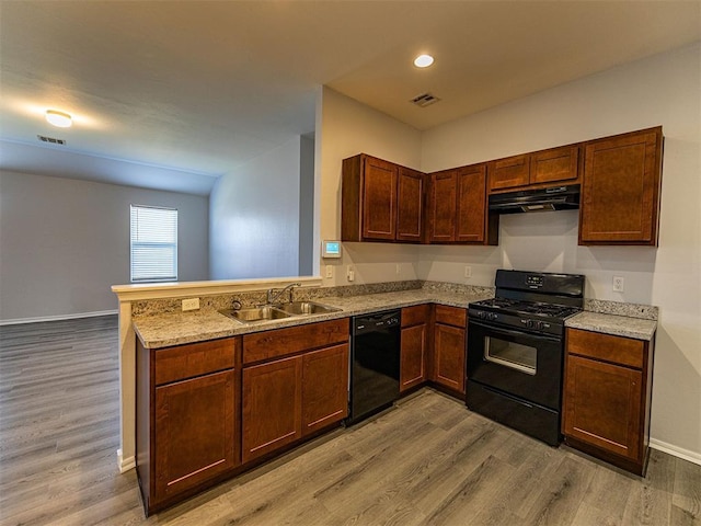 kitchen featuring black appliances, under cabinet range hood, light wood finished floors, and a sink