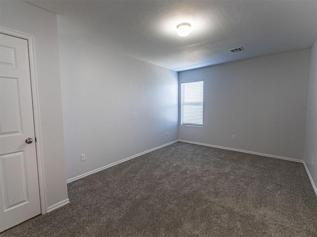 unfurnished room with dark colored carpet, visible vents, and baseboards