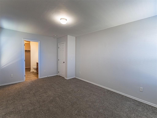 empty room with dark colored carpet and baseboards