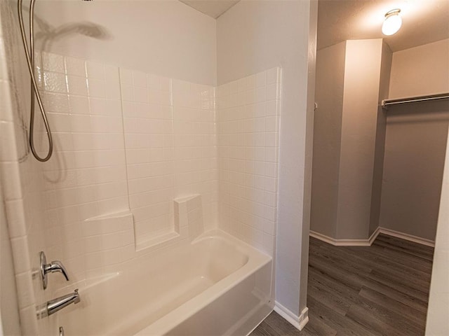 full bathroom featuring bathtub / shower combination, a spacious closet, baseboards, and wood finished floors