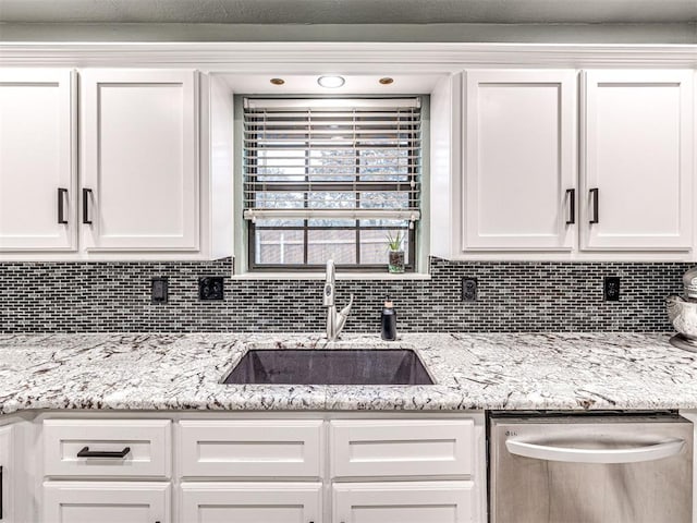 kitchen featuring stainless steel dishwasher, white cabinetry, and a sink