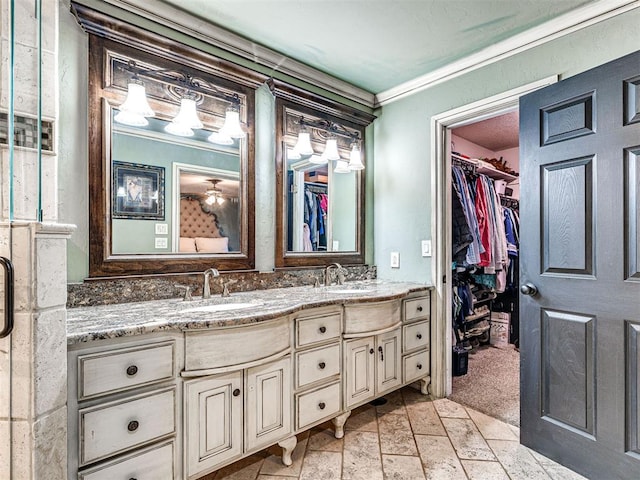 full bathroom featuring double vanity, crown molding, a walk in closet, and a sink