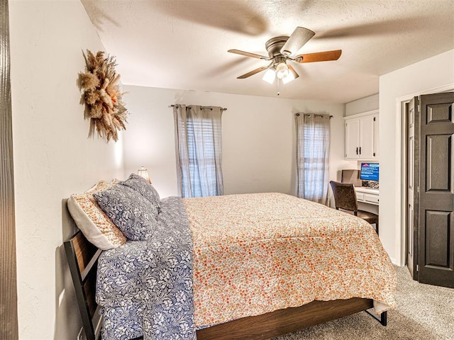 bedroom featuring carpet floors, built in study area, ceiling fan, and a textured ceiling