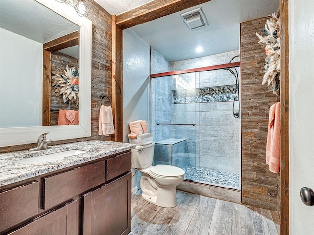 bathroom with visible vents, a shower stall, toilet, and wood finished floors