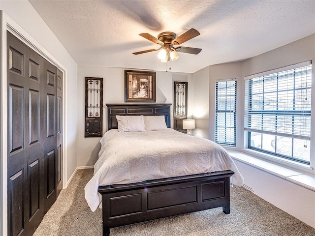 bedroom with carpet, a closet, ceiling fan, a textured ceiling, and baseboards