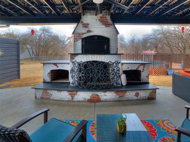 view of patio featuring an outdoor brick fireplace and fence