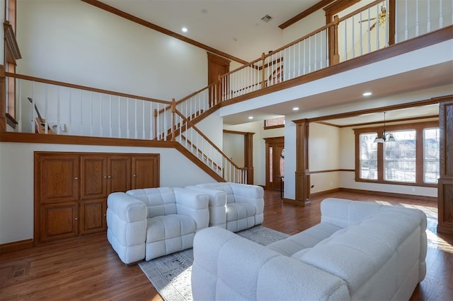 living area with decorative columns, crown molding, baseboards, and wood finished floors