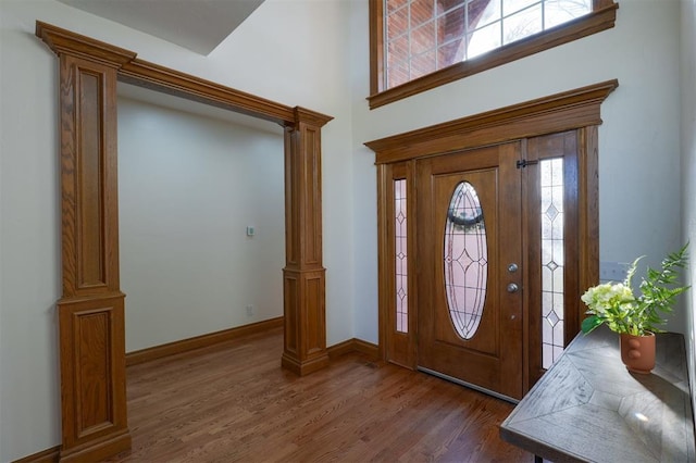 foyer featuring ornate columns, baseboards, and wood finished floors