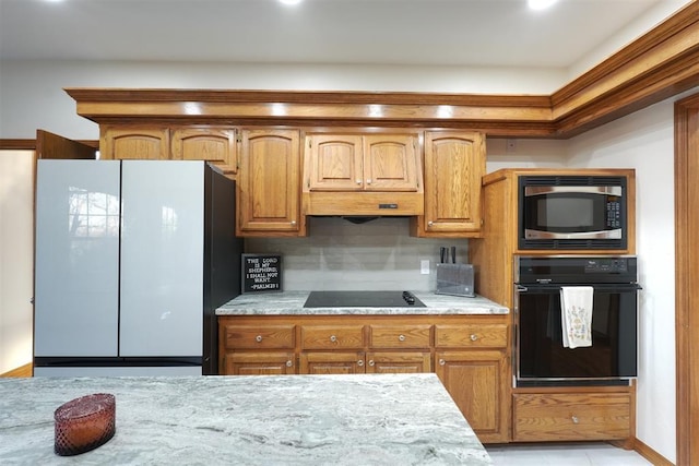 kitchen with black appliances, brown cabinetry, and decorative backsplash