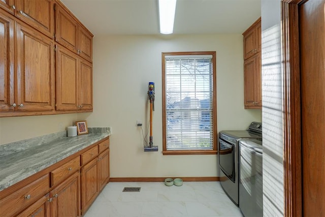 kitchen featuring brown cabinets, visible vents, baseboards, and separate washer and dryer