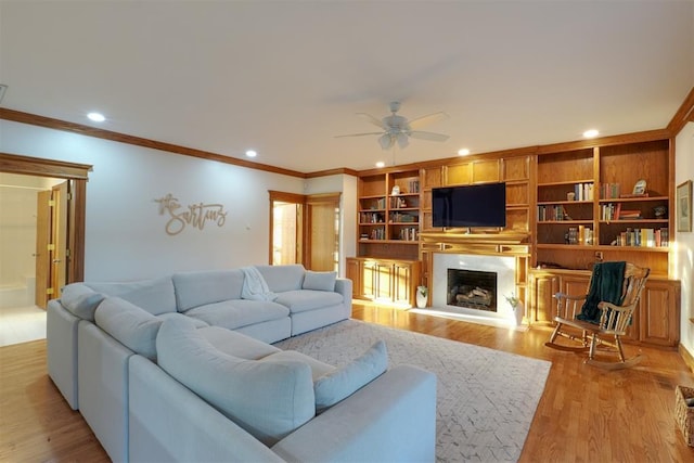 living room featuring ornamental molding, a high end fireplace, light wood finished floors, and recessed lighting