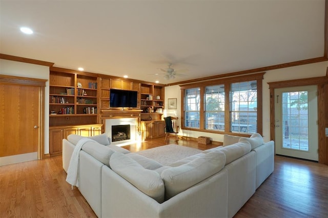 living room featuring a fireplace, recessed lighting, ornamental molding, ceiling fan, and light wood-type flooring