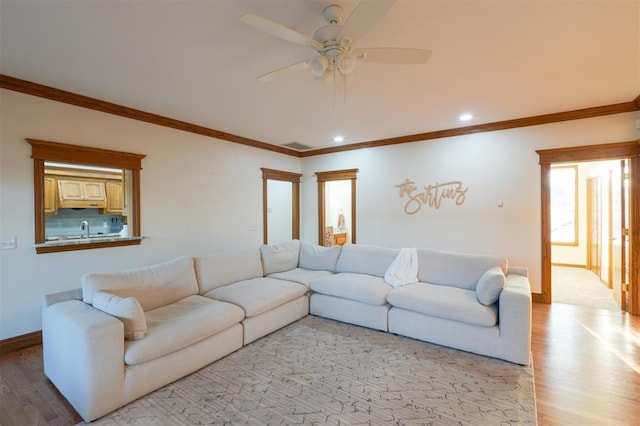 living area with crown molding, light wood-style flooring, and baseboards