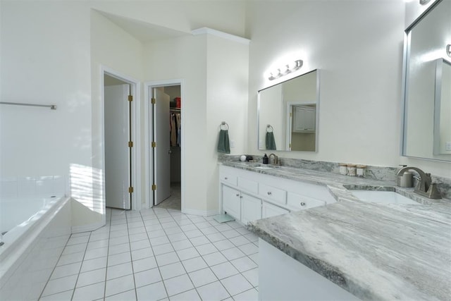 bathroom featuring a spacious closet, double vanity, a sink, and tile patterned floors