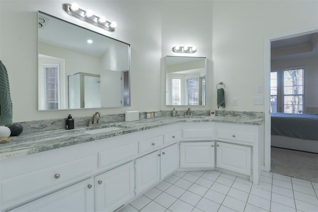 ensuite bathroom featuring a shower stall, double vanity, a sink, and tile patterned floors