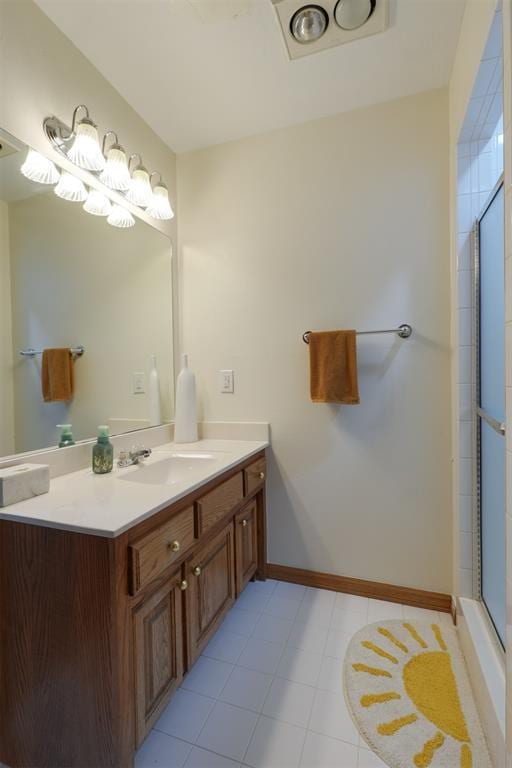 full bathroom featuring a shower with door, vanity, and baseboards