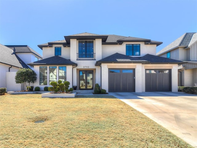 view of front of home with stucco siding, french doors, concrete driveway, a front yard, and an attached garage