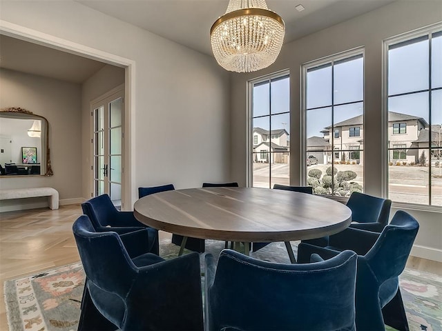 dining space featuring plenty of natural light, baseboards, an inviting chandelier, and a residential view