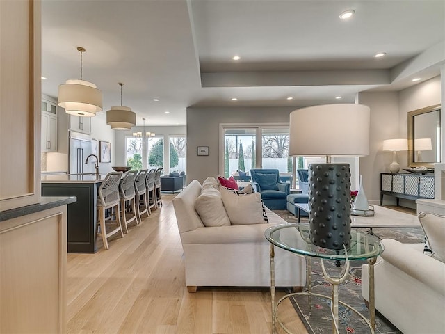 living area with recessed lighting, light wood-style flooring, and a tray ceiling